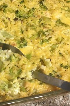 a casserole dish with broccoli and cheese in it being cut by a pair of tongs