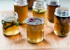 several jars filled with different types of tea on top of a wooden table next to each other