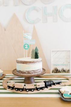 a train themed birthday party with a cake and cupcakes on a table top