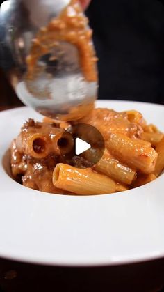 someone is adding sauce to some pasta on a plate