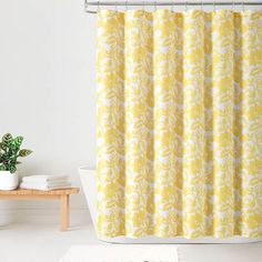 a bathroom with a yellow shower curtain next to a potted plant