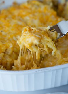 a spoon full of macaroni and cheese being lifted from a casserole dish