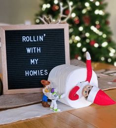 an elf's toilet paper roll sitting on top of a table next to a sign that says rollin'with my homes