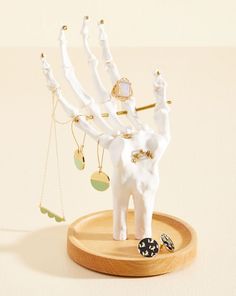 a white elephant figurine on a wooden base with jewelry hanging from it's back