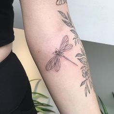 a woman's arm with a dragonfly tattoo on the left side of her arm