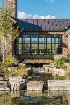 a house with a pond in front of it and stone steps leading up to the roof