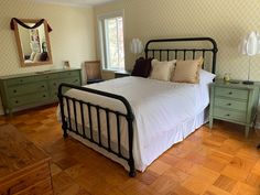 a bed sitting on top of a hard wood floor next to a dresser and mirror