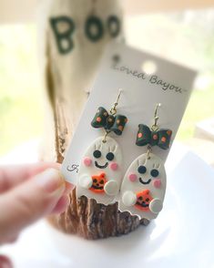 a pair of panda bear earrings with bows on them sitting on a white plate next to a card