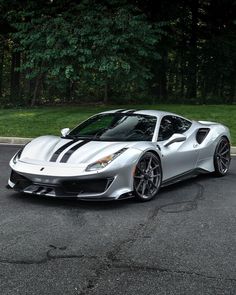 a silver sports car is parked on the side of the road in front of some trees