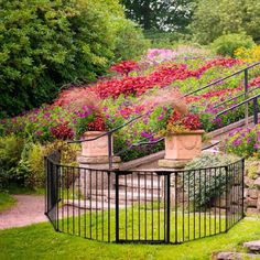 an iron fence with flowers growing on it and stairs leading up to the top level