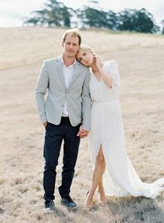 a man and woman standing next to each other in the middle of an open field