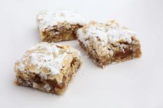 four pieces of dessert sitting on top of a white table next to some powdered sugar