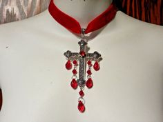 "Red velvet choker with large ornate gothic/medieval style cross pendant. the cross has a red glass \"rhinestone\" in its center, plus drippy red beads hanging from it. the choker adjusts between 13.5 to 16.5\",  so will fit necks up to about 15.5\" around  (should be a little loose, so that the cross will lay nicely on your chest). cross, with bead drops, is about 2\" wide, 4.5\" tall." Gothic Cross Pendant Jewelry For Halloween, Adjustable Gothic Cross Pendant Jewelry, Adjustable Red Gothic Jewelry, Red Gothic Cross Necklace, Handmade Red Crucifix Jewelry, Red Adjustable Cross Necklace, Adjustable Red Cross Necklace, Ornate Cross, Ribbon Choker Necklace