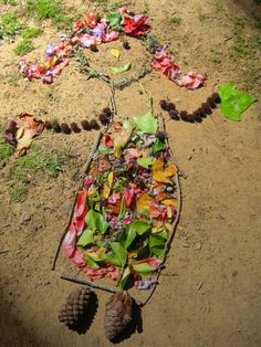 a wheelbarrow filled with leaves and pine cones on the ground next to grass