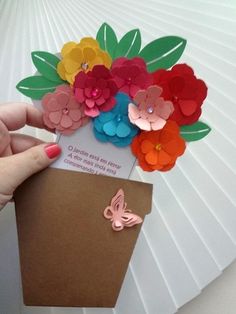 a hand holding a card with flowers on it and a butterfly attached to the back