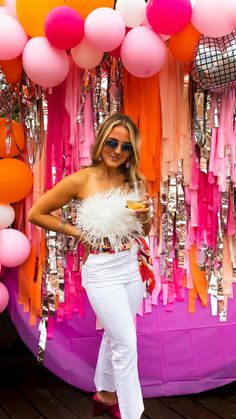 a woman standing in front of a display of balloons and tassels with her hands on her hips