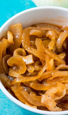 a white bowl filled with sliced onions on top of a blue table