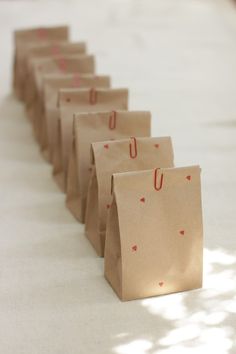 small brown paper bags lined up on a table with red hearts drawn on them and the handles are down