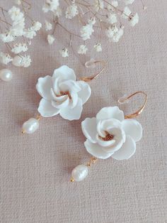 two white flowers with pearls on them are sitting next to some small branches and flowers