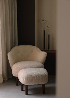 a white chair and ottoman in front of a window