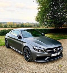 a grey car parked on top of a gravel road