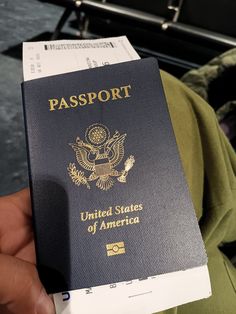 a person holding a us passport in their hand while sitting on a train car seat