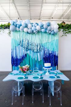 a table set up with balloons and streamers on the wall for an ocean themed party