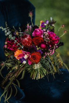 a bouquet of flowers sitting on top of a blue velvet chair