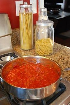 a large pot filled with pasta and sauce on top of a stove next to a blender