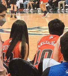 a group of young people sitting on top of a basketball court next to each other