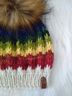 a multicolored knit hat with a fur pom