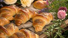 freshly baked croissants sitting on top of a wooden table next to flowers