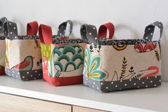 three small bags are lined up on a shelf with polka dots and birds in them