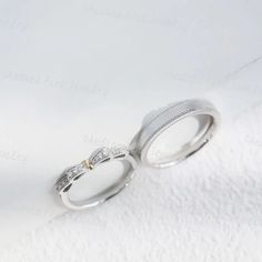 two wedding rings sitting on top of a white cloth covered table next to each other