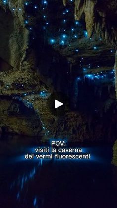 a cave filled with lots of blue lights in the night sky and surrounded by water