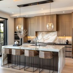 a kitchen with marble counter tops and bar stools next to an open floor plan