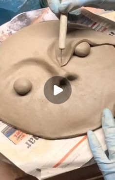 someone is making a clay face on a piece of pottery