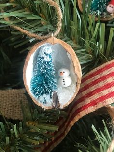 a christmas ornament with a snowman in the middle and a pine tree behind it