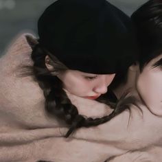 two women are wrapped up in blankets and one is wearing a black hat with braids