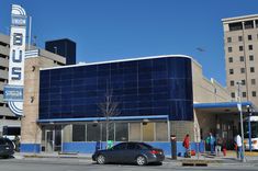 cars are parked in front of a building with a blue sign on the side of it