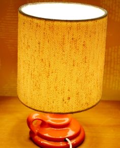 an orange lamp sitting on top of a table next to a yellow lampshade