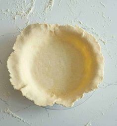 an uncooked pie crust on a white surface with some yellow liquid in it