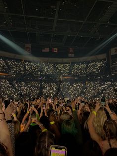 a crowd of people at a concert taking pictures with their cell phones in front of them