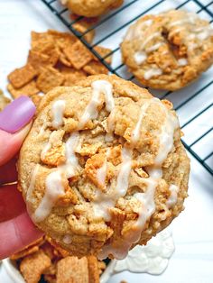 a person holding a cookie with icing on it and some crackers in the background