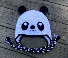 a crocheted panda bear hat on top of a wooden floor with black and white stripes