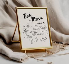 a menu sign sitting on top of a table next to a white cloth covered bed