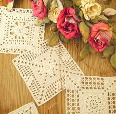 two crocheted doily on a wooden table with flowers in the center and another piece of lace next to it