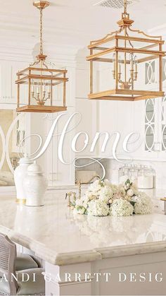 a white kitchen with gold accents and chandeliers