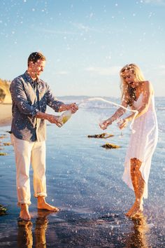 a man and woman are throwing confetti into the air at the beach while standing in the water