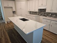 a kitchen with white cabinets and an island countertop in the middle of the room